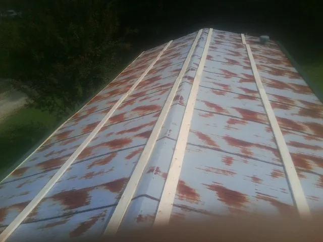 Rusted metal roof panels with new wood purlins before replacement — Storm Damage Roof Repair in Staffordsville by Roofing Brothers