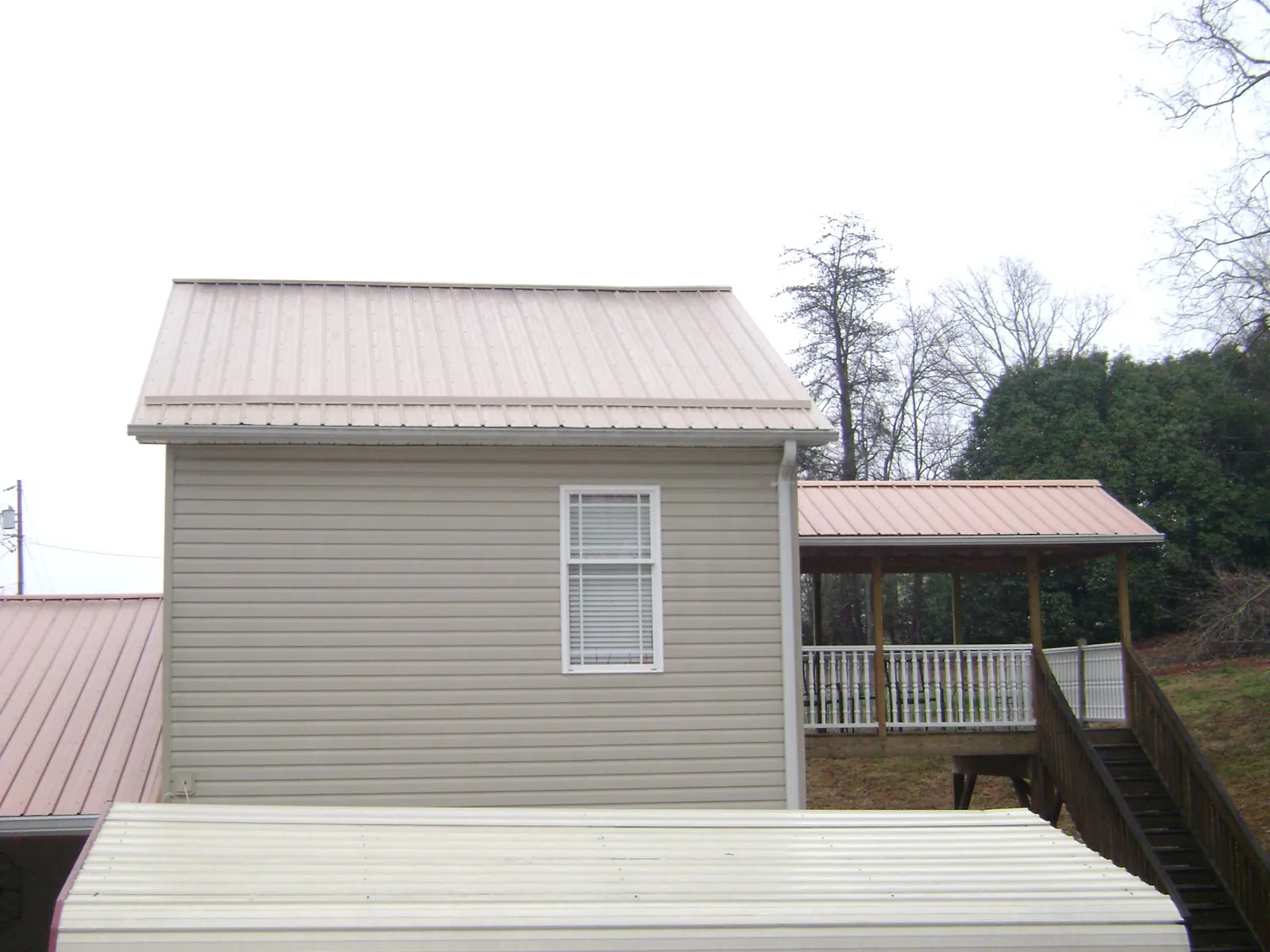 Tan metal roofs on a two story addition and attached porch, from a Roof Replacement job in Staffordsville